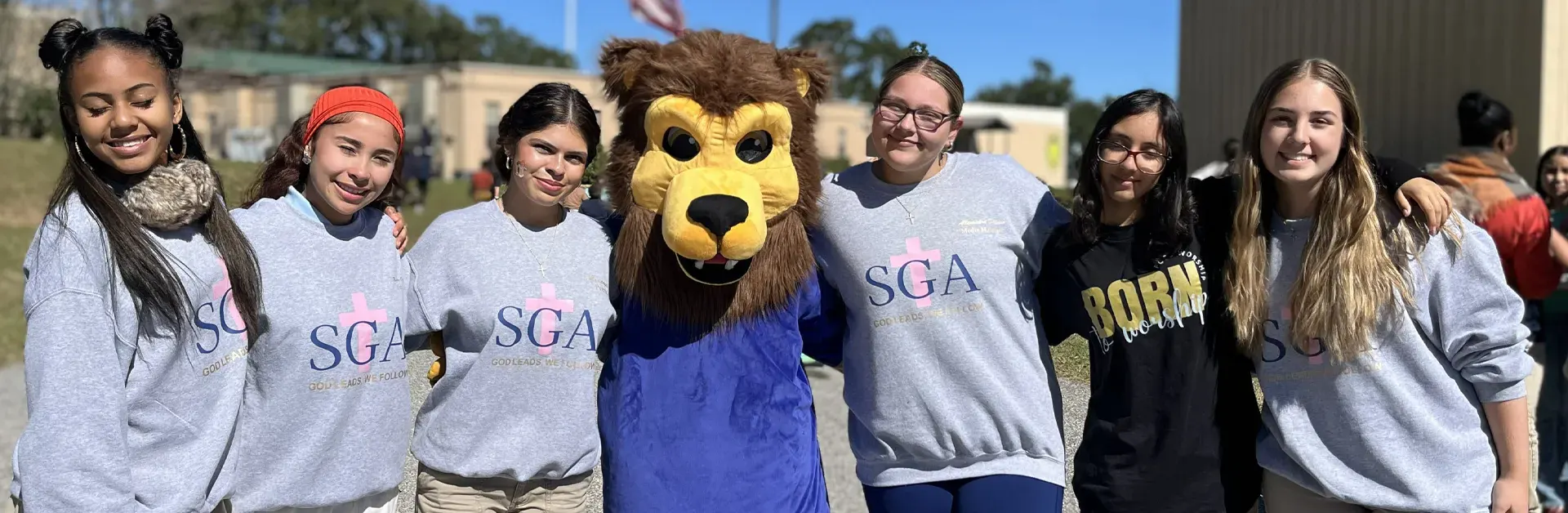 FCC School student government members outside with the Lions mascot
